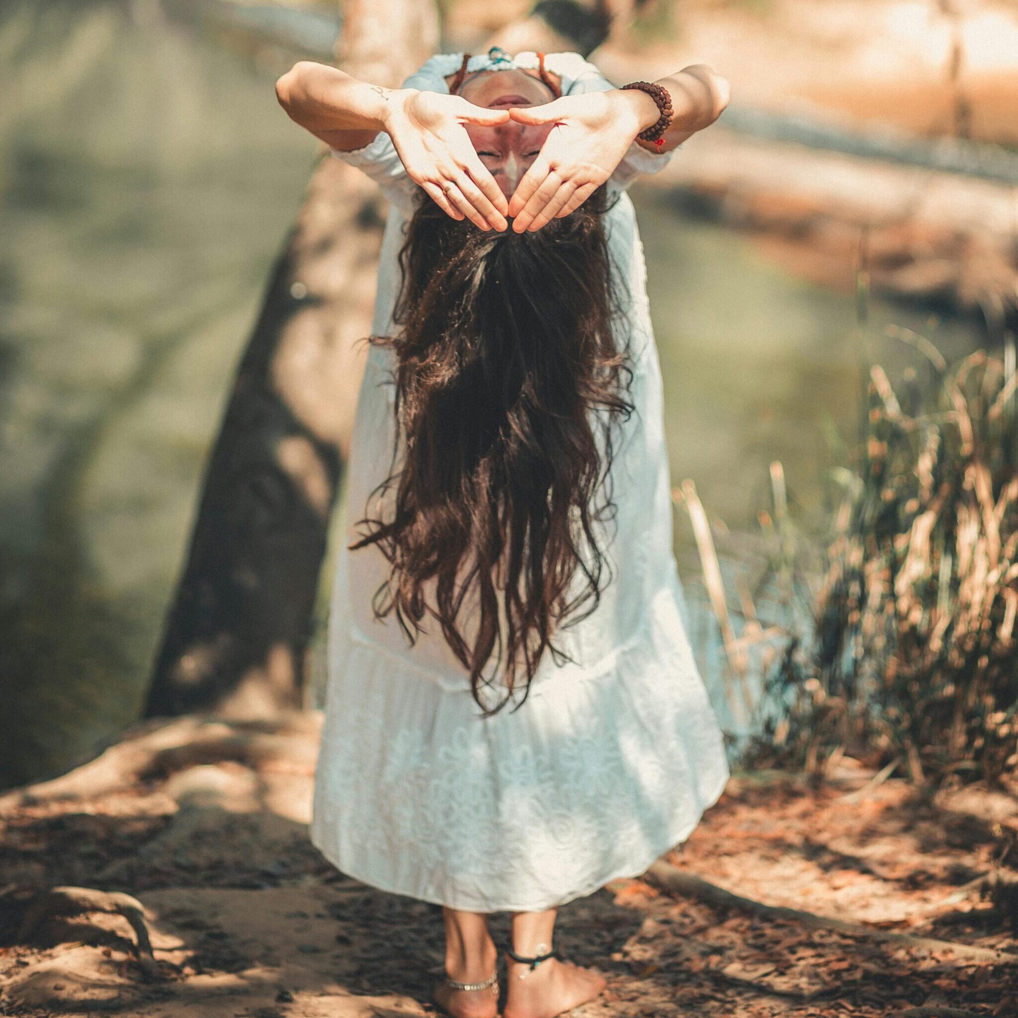 Une femme avec de longs cheveux qui performe une seance de soins yoga, soin énergétique, Tzifa par une journée ensoleillé accompagnements appel d'âme a âme