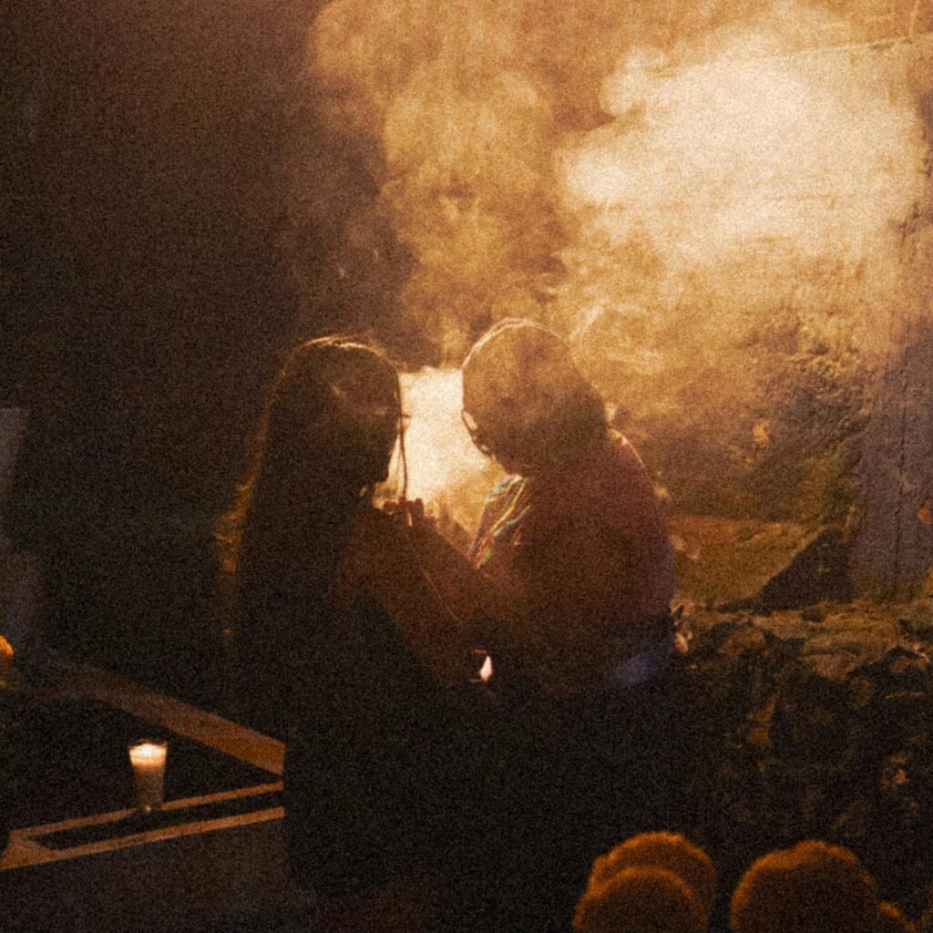 Two people perform a mystical evening ritual with candlelight and smoke outdoors.